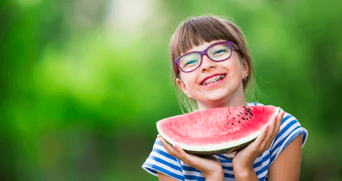 child smiling holding watermelon slice