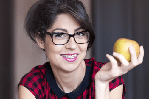 lady in glasses holding apple smiling